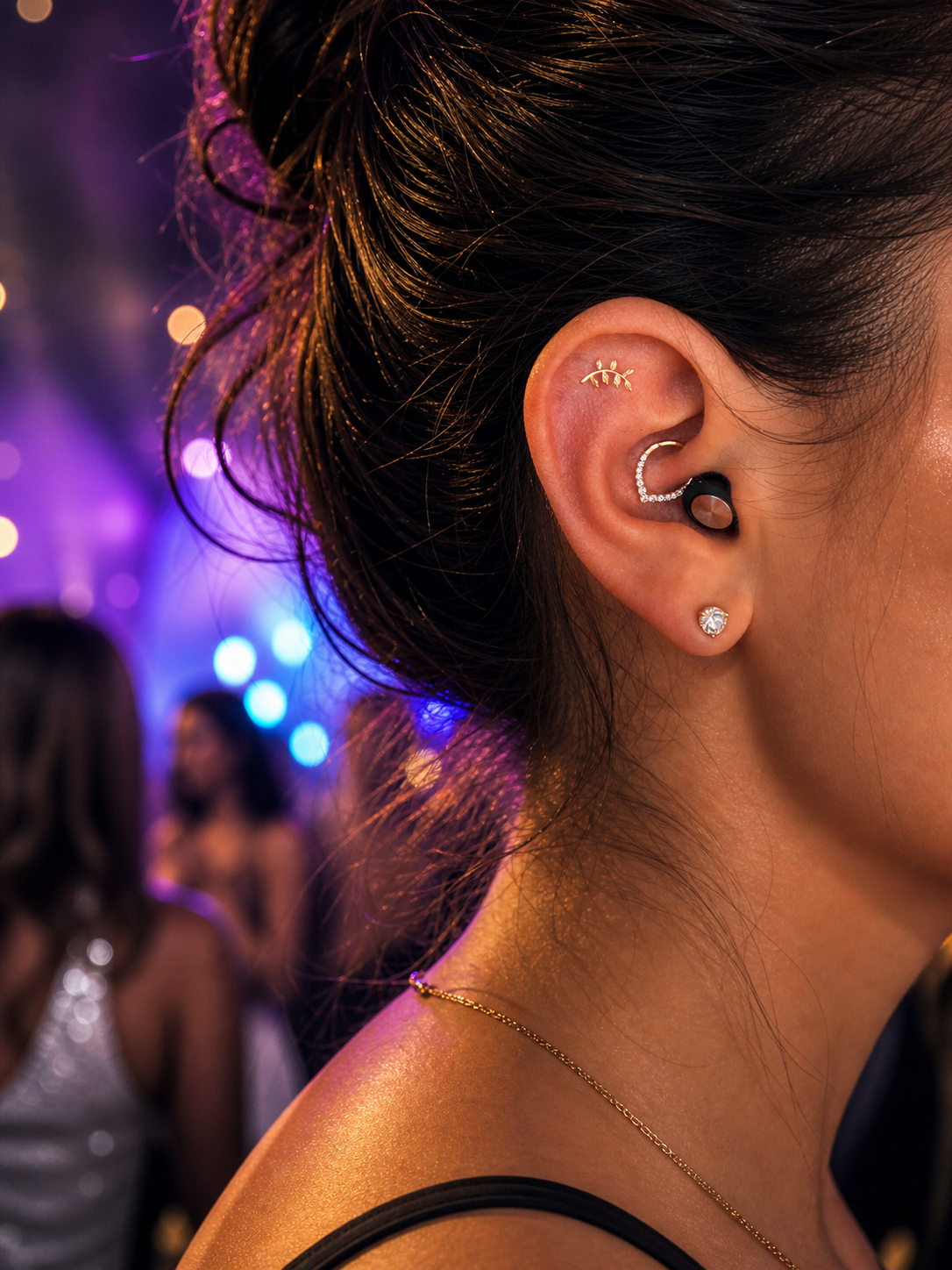 Lyve AIr earplug demonstrated Close-up in a person's ear with multiple earrings against a blurred background